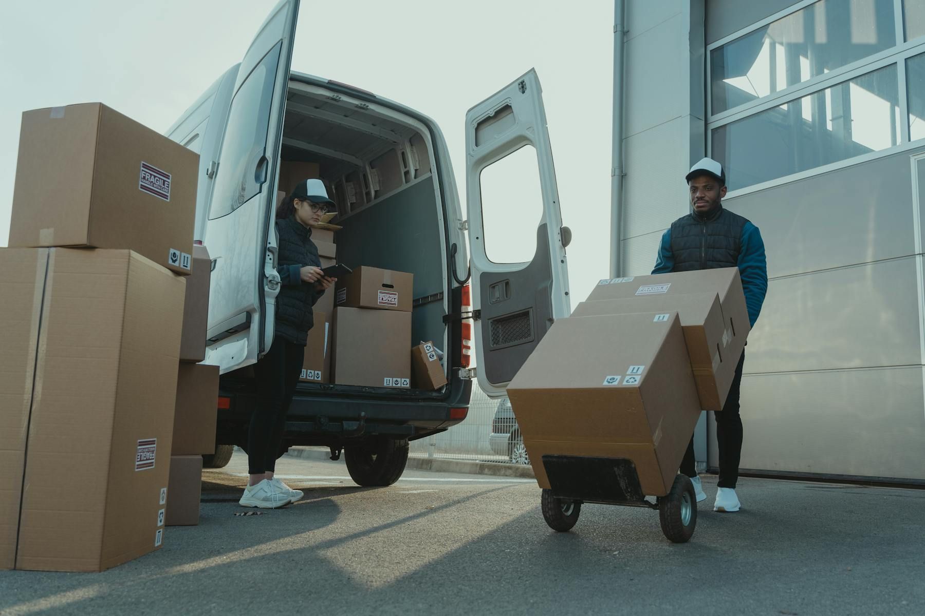 Two delivery workers loading parcels into a van for distribution.